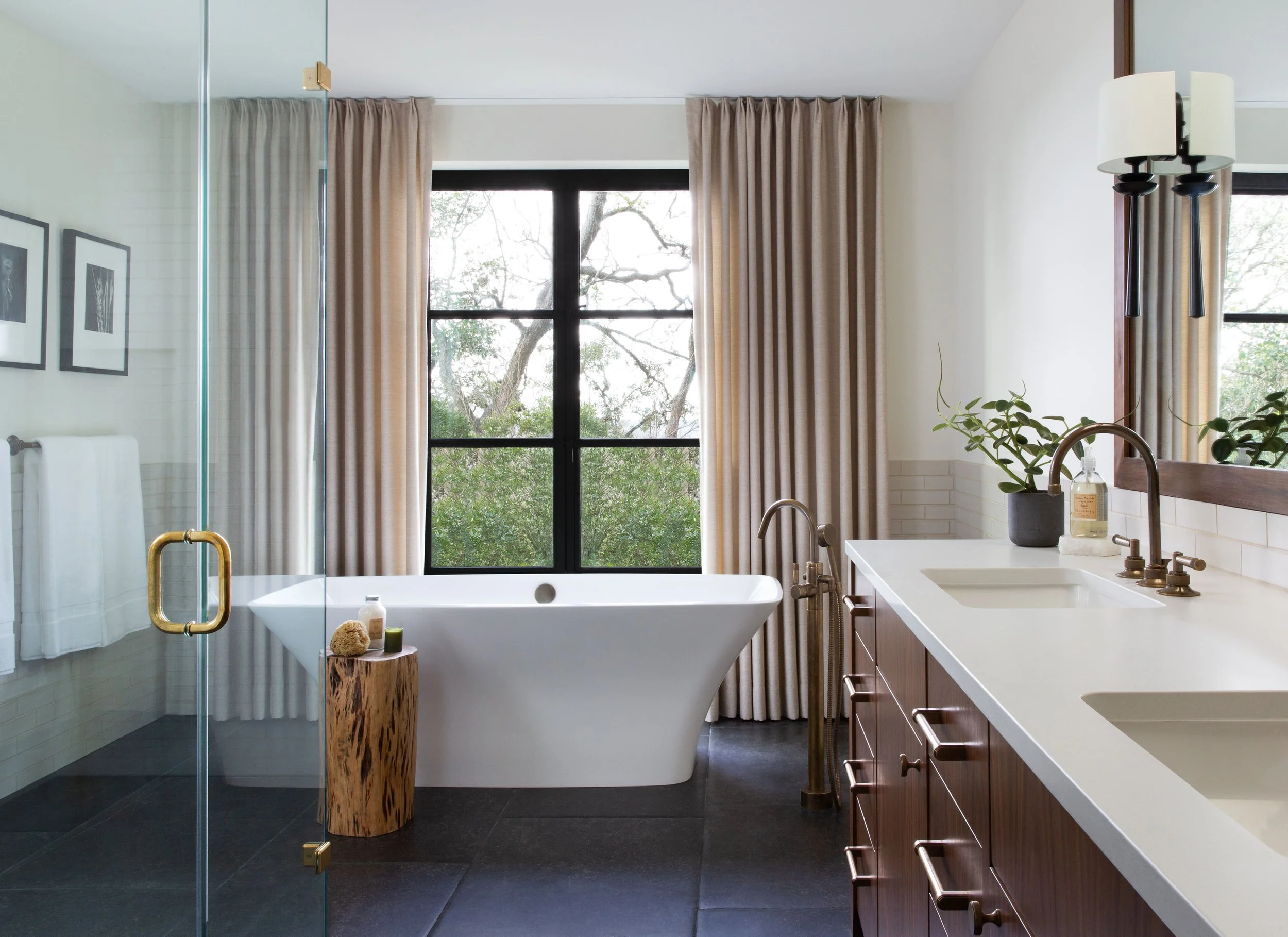 Primary bathroom with freestanding tub, custom walnut vanity, Belgian bluestone tile floor, steel windows, and custom drapery.