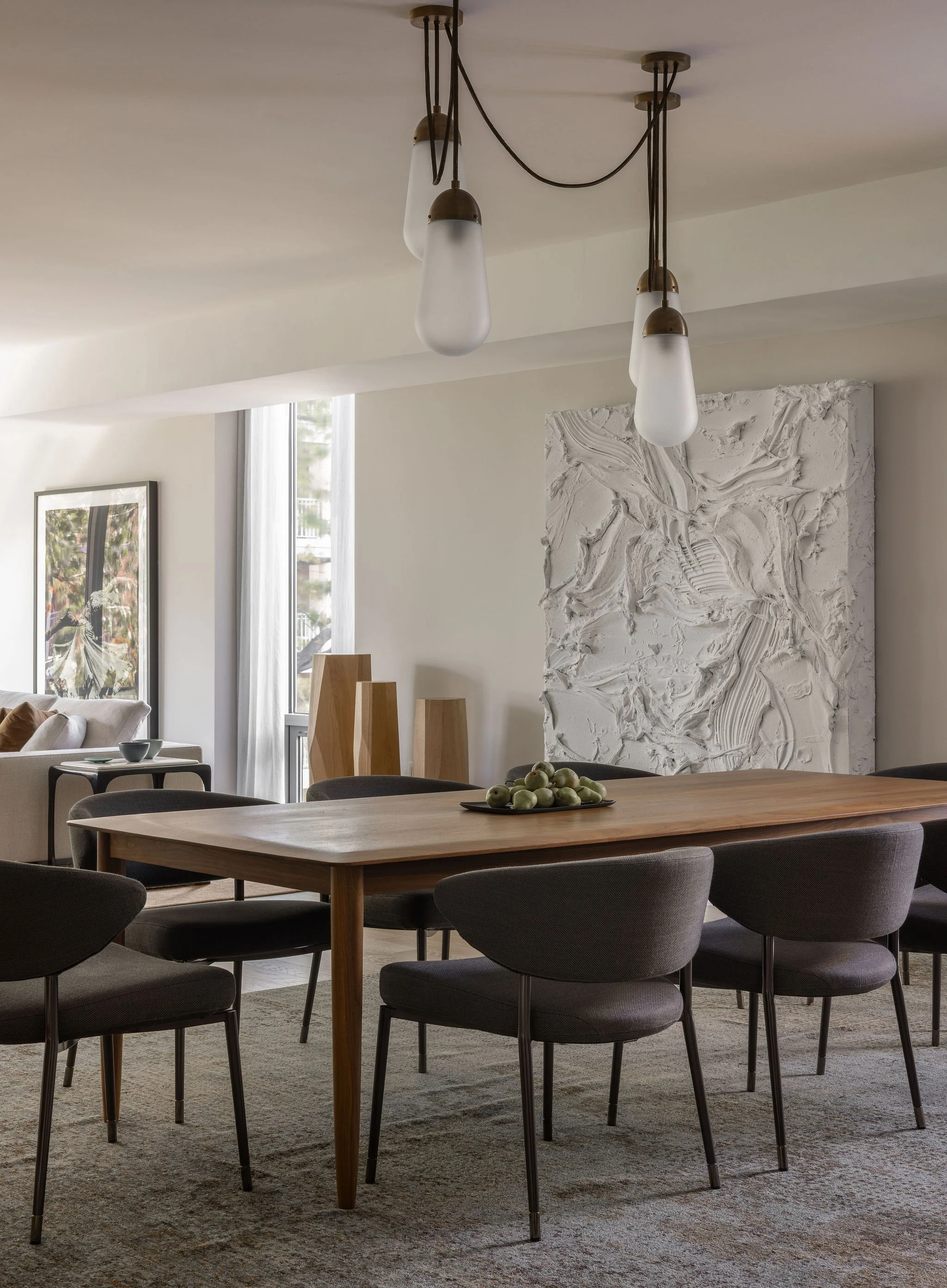 Walnut dining table beneath an Apparatus lariat chandelier in a Georgetown condo by Austin interior designer Laura Roberts Design, with views to a commissioned Jason Martin painting and a Ruth St. Denis photograph.