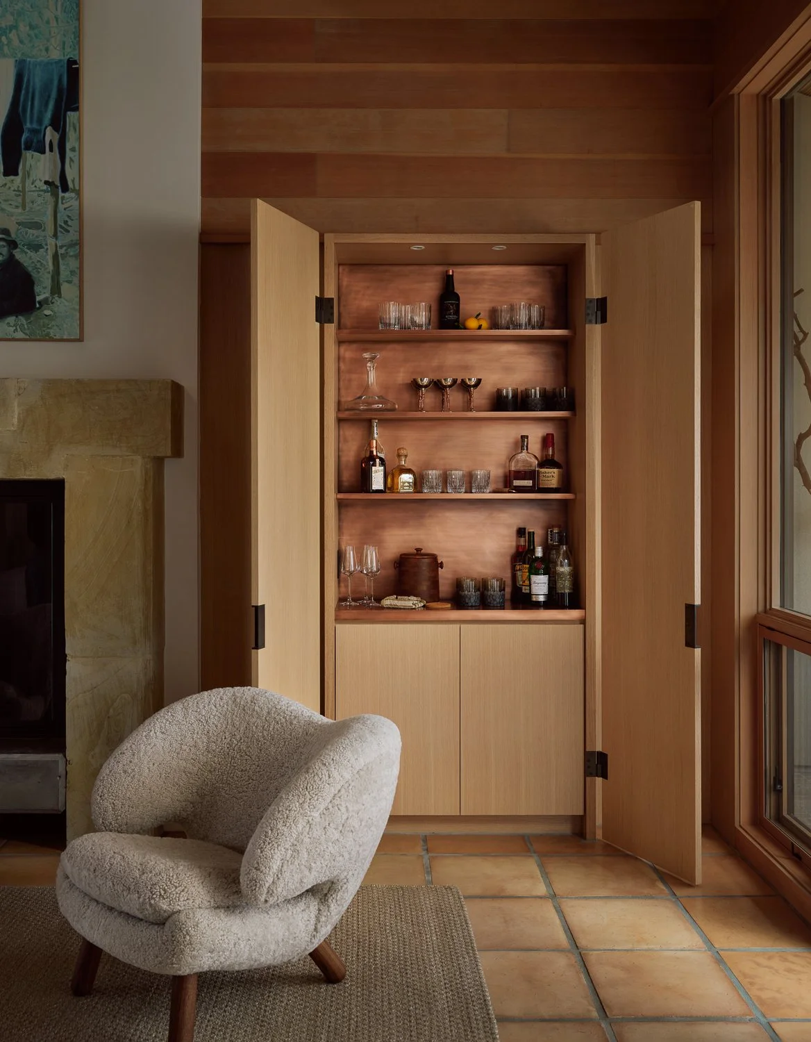 Custom white oak bar cabinet with a copper-lined interior in the Sonoma living room, paired with a Finn Juhl Pelican chair and original Saltillo tile floors.