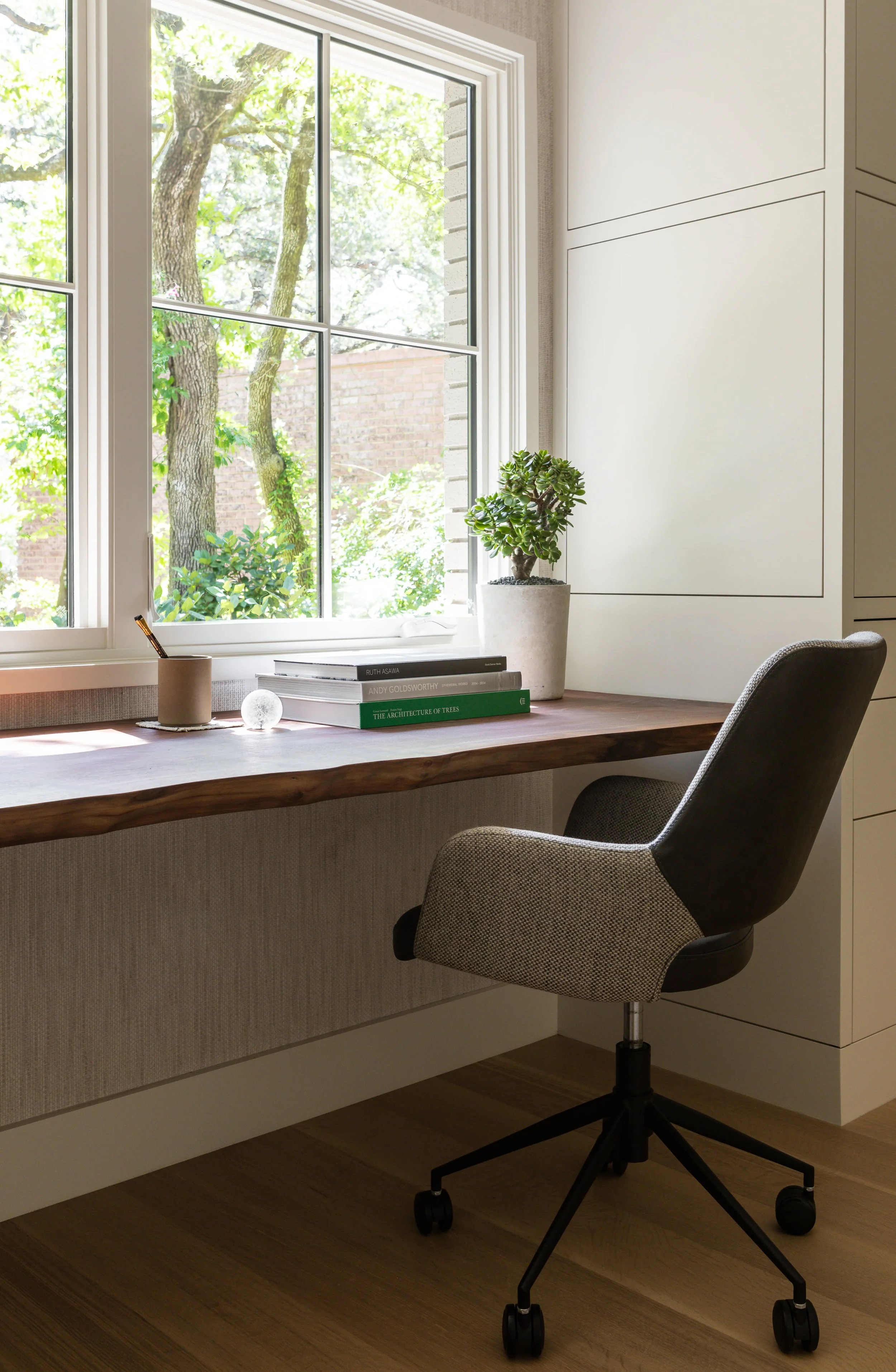 Austin home office vignette with live-edge walnut cantilevered desk, upholstered leather desk chair, custom painted millwork, and window view.