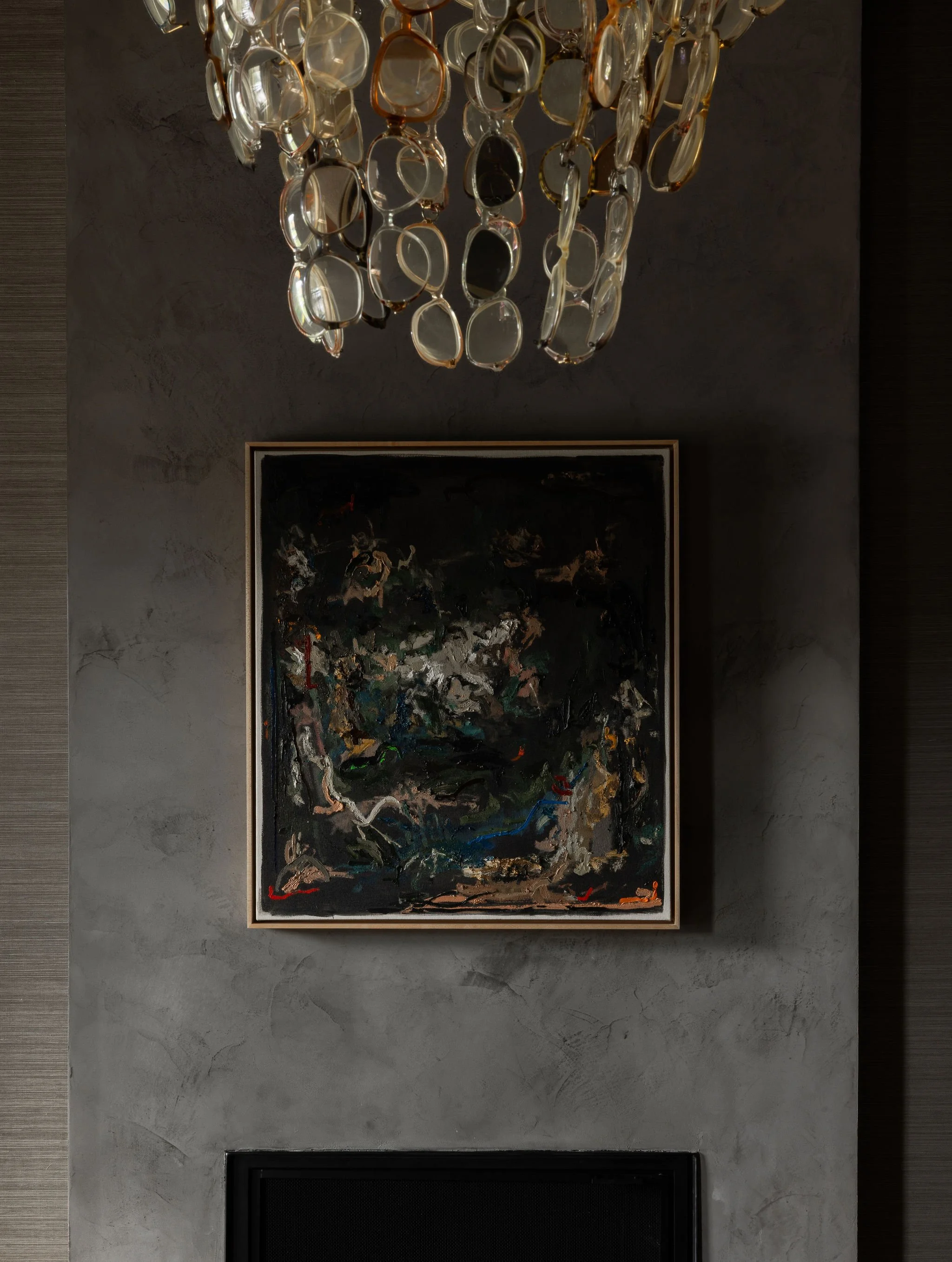 Detail of a dark plaster fireplace in the dining room with a commissioned abstract painting by Hue Thi Hoffmaster, dark grasscloth walls, and the Spectacle chandelier by Stuart Haygarth.