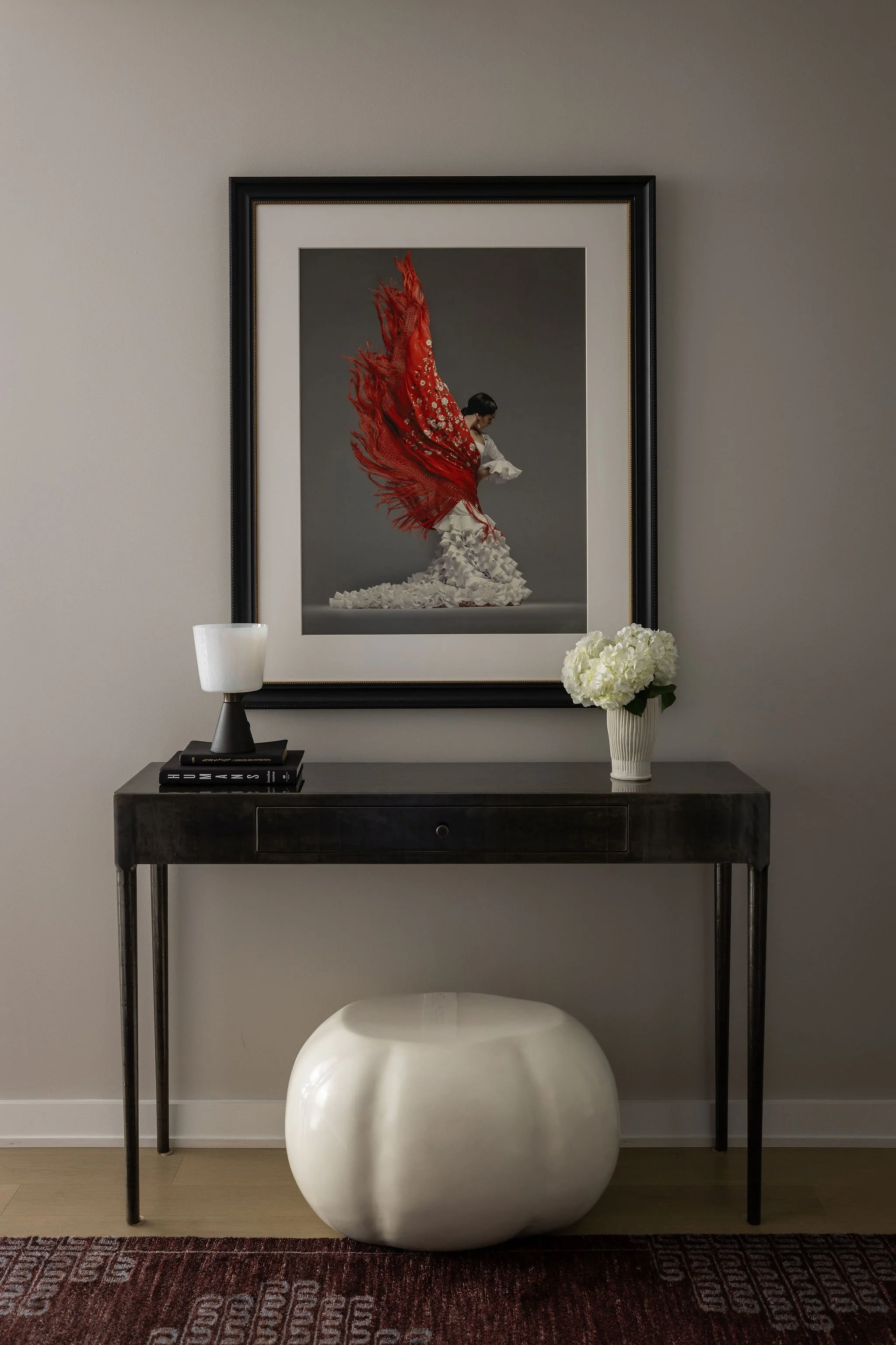 Foyer of a Georgetown condo by Austin interior designer Laura Roberts Design, featuring a dramatic flamenco dancer artwork displayed above a finely crafted steel console, creating a bold and elegant first impression.