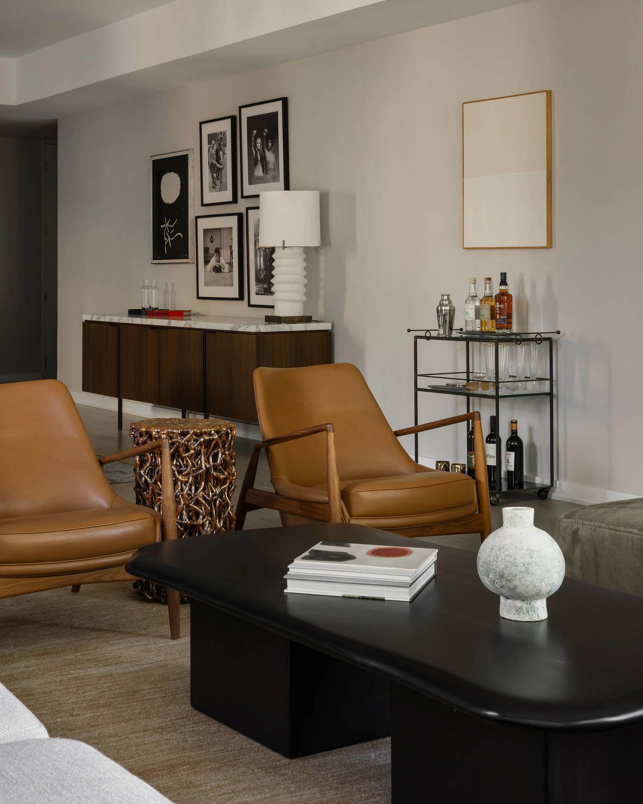 View from living room to dining room in a Georgetown condo by Austin interior designer Laura Roberts Design, featuring a styled bar cart with artwork by Ethan Cook and a salon-style art installation reflecting the client’s personal collection.