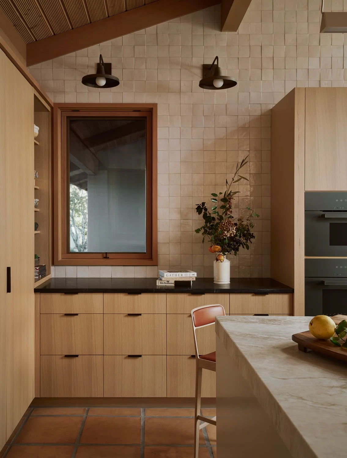 Custom kitchen with white oak millwork, integrated panel-ready refrigeration, Miele wall ovens, soapstone perimeter counters, and a Taj Mahal quartzite island.