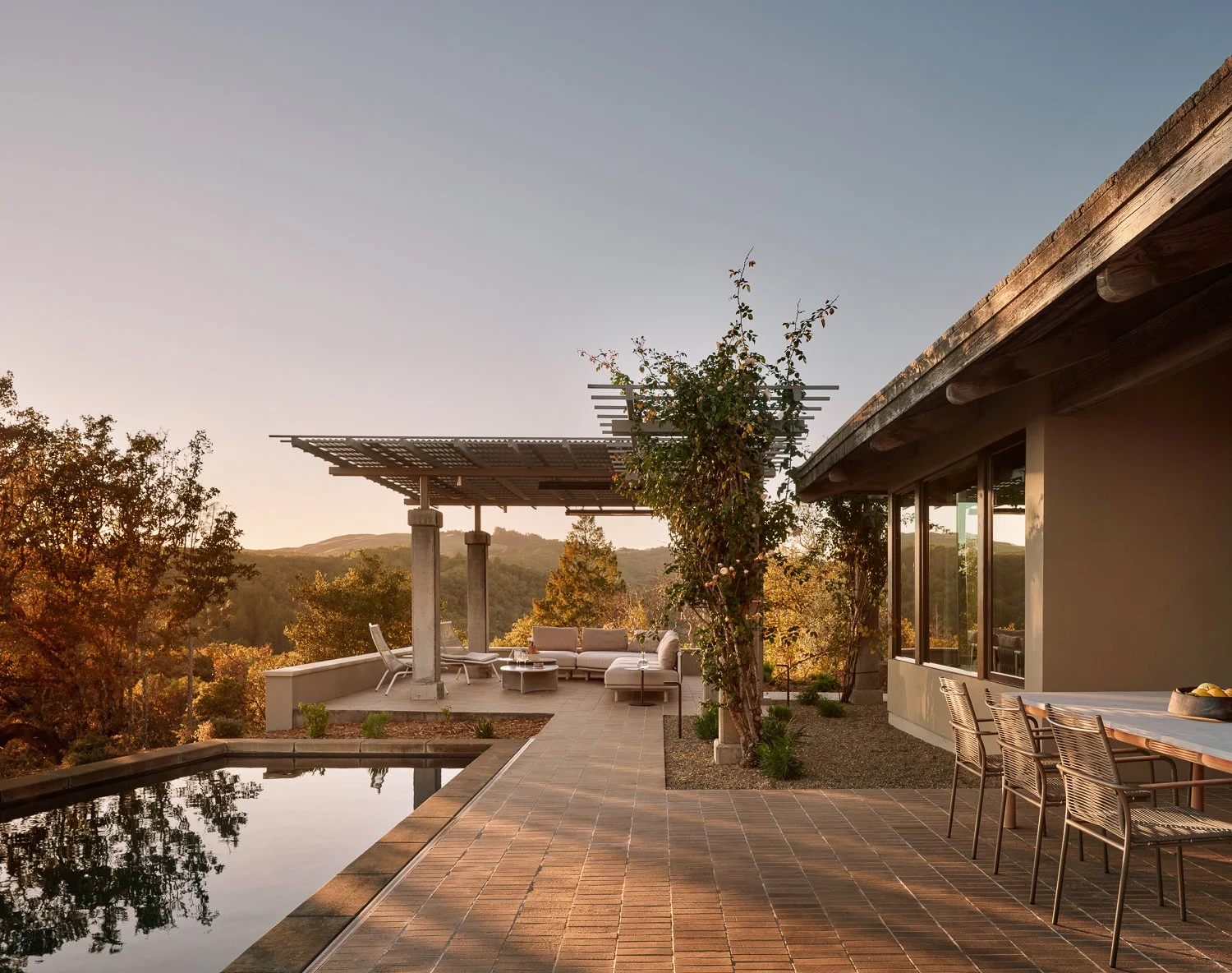Outdoor living by Laura Roberts Design featuring expansive wine country views, architectural trellis shading, and layered landscape design, with Sutherland outdoor dining and Roda lounge seating.