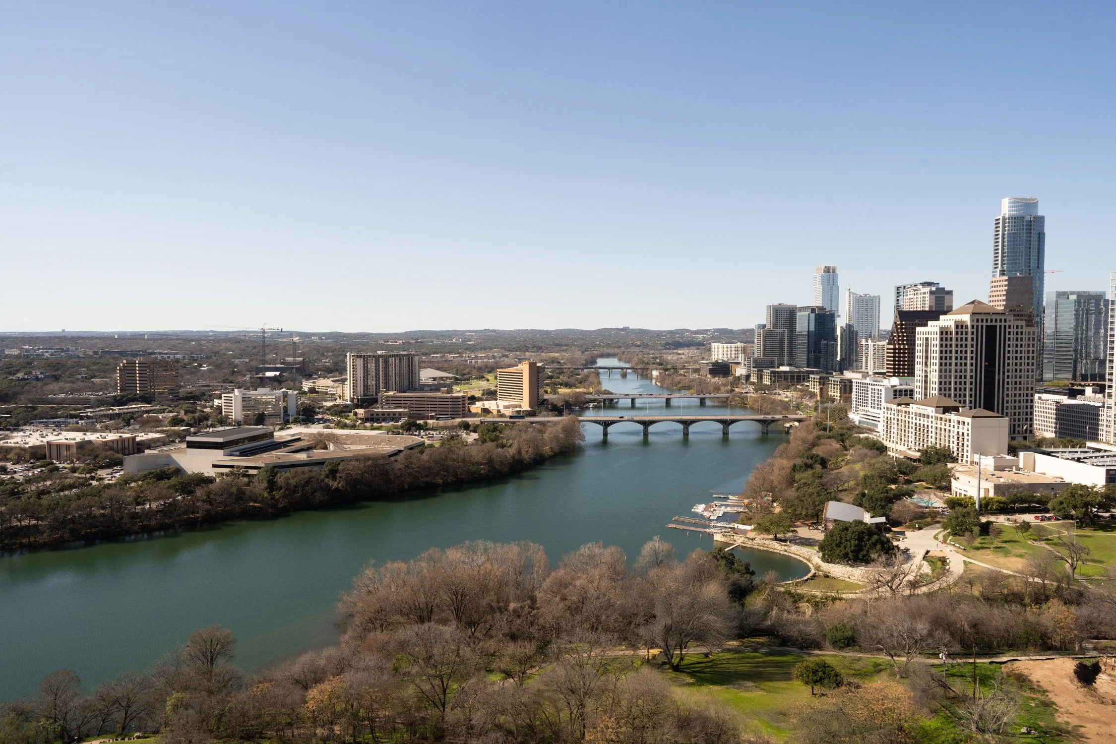Downtown Austin skyline and Lady Bird Lake viewed from a Rainey Street condo, with city towers, bridges, and expansive river views.