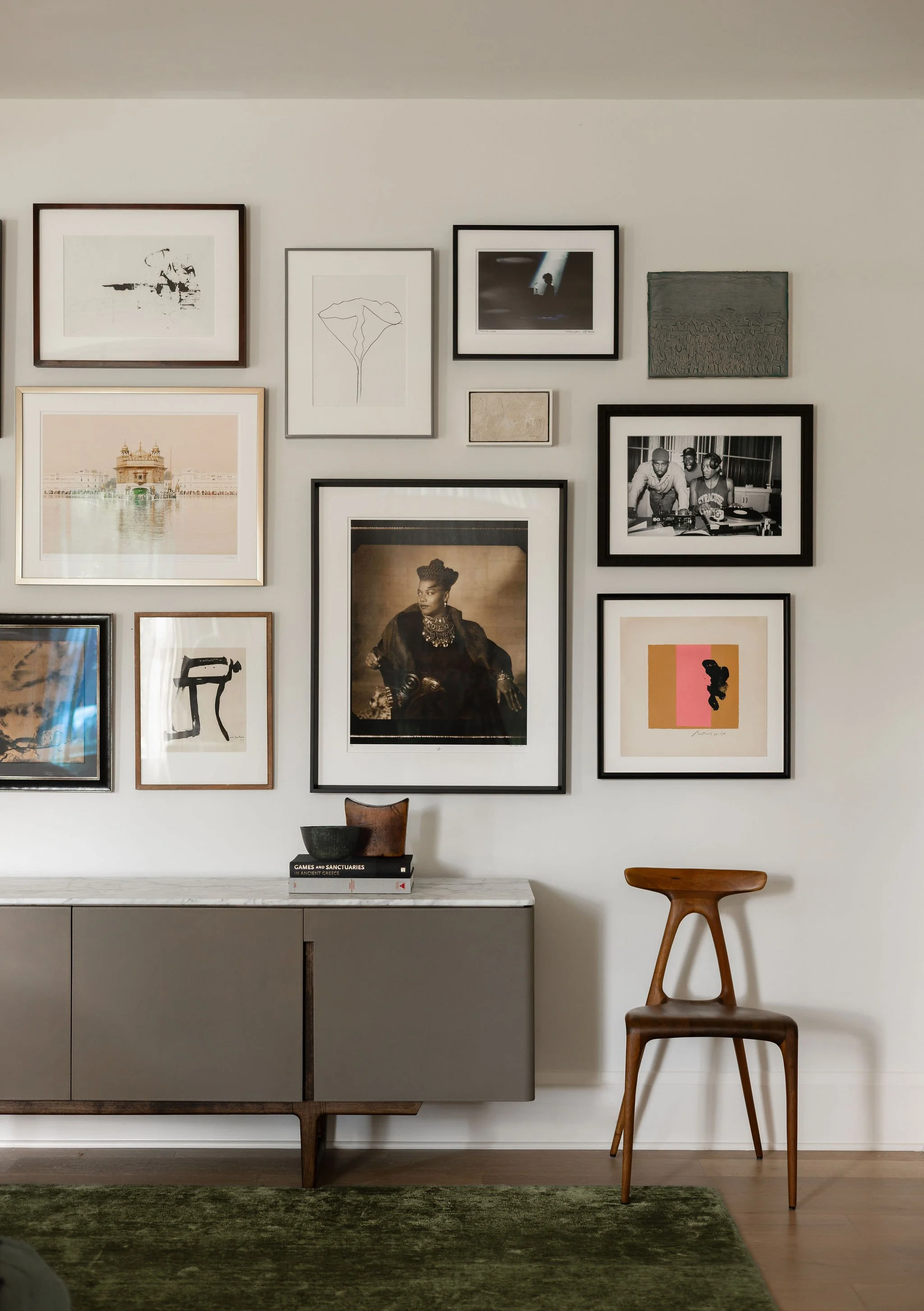 Detail of the salon style gallery wall with Queen Latifah, Cassina cabinet and walnut Alpha chair.
