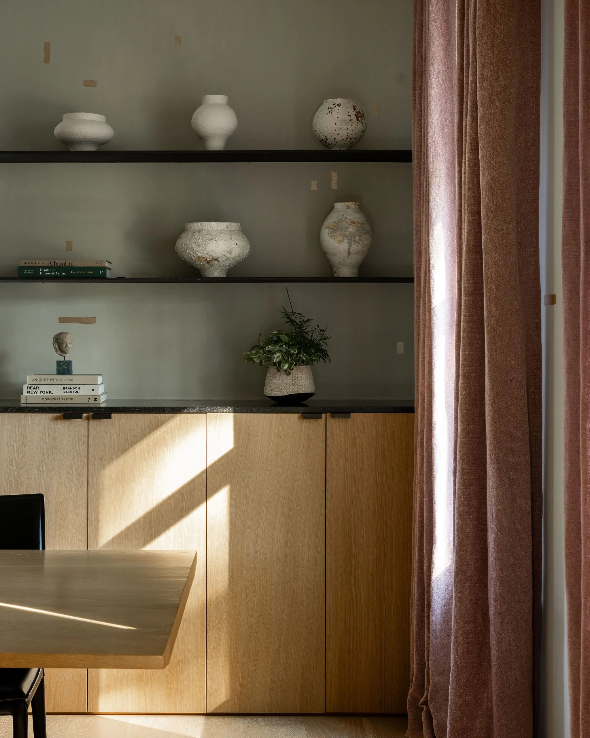 Home office adjacent to the wine room in a McLean, VA home featuring coordinating Porter Teleo wallpaper, custom white oak built-ins, steel shelving, and a curated collection of Moon jars by Jane Yang-D’Haene.