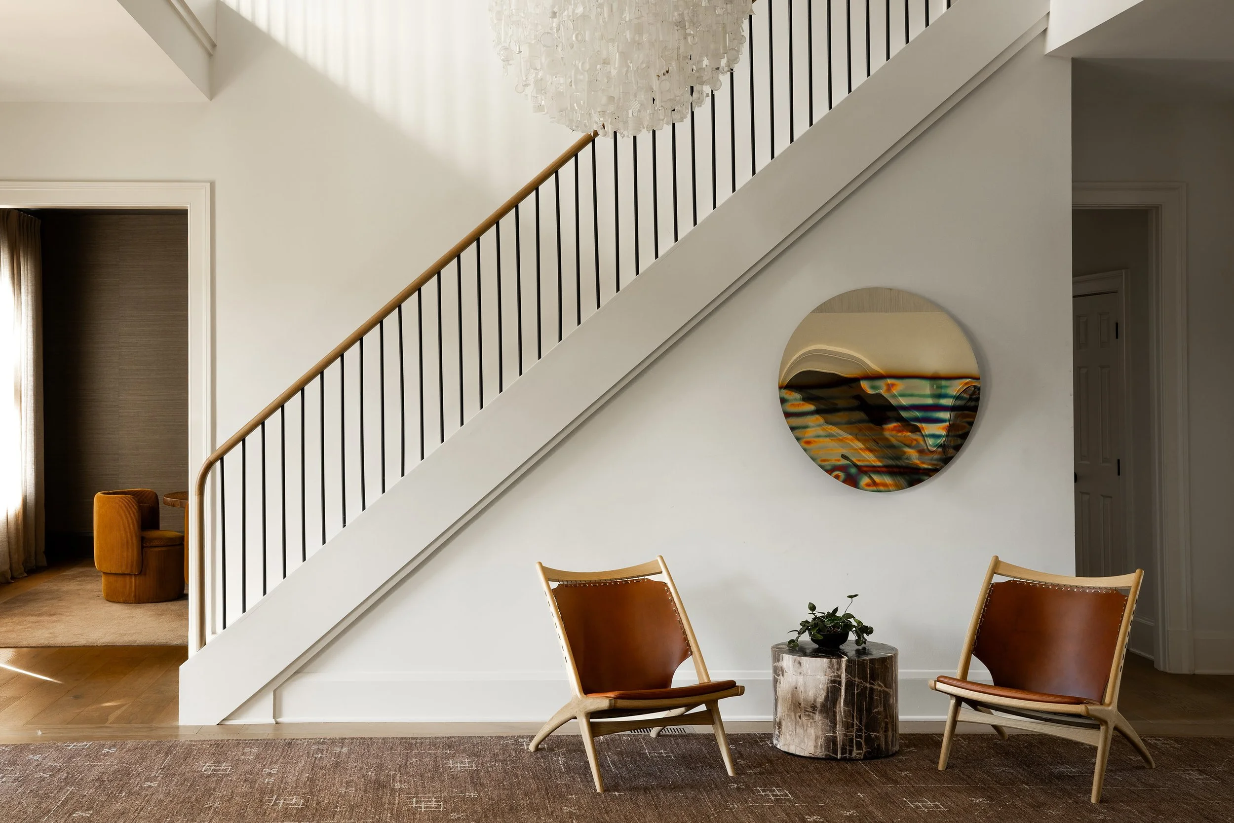 Modern stairwell renovation with Stuart Haygarth Tide Chandelier, Anton Hendrick Denys mirror, custom Battilosi rug, petrified wood side table by Austin Interior Designer Laura Roberts Design