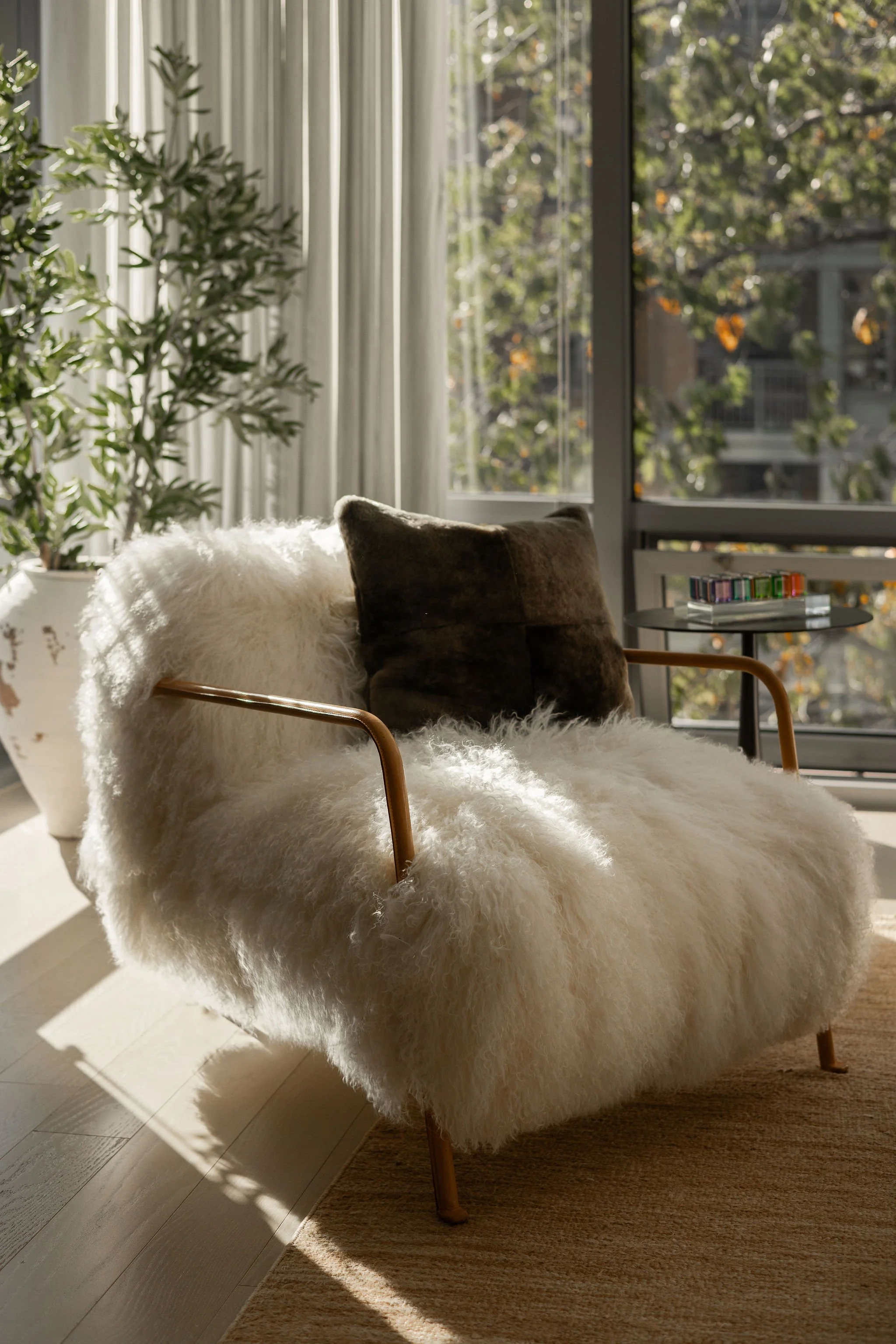 Detail of a Bruxelles armchair by Baxter Italy with leather arms, positioned by a large window in a Georgetown condo living room designed by Austin interior designer Laura Roberts Design, styled with vintage Vasa Cubes in cast acrylic.