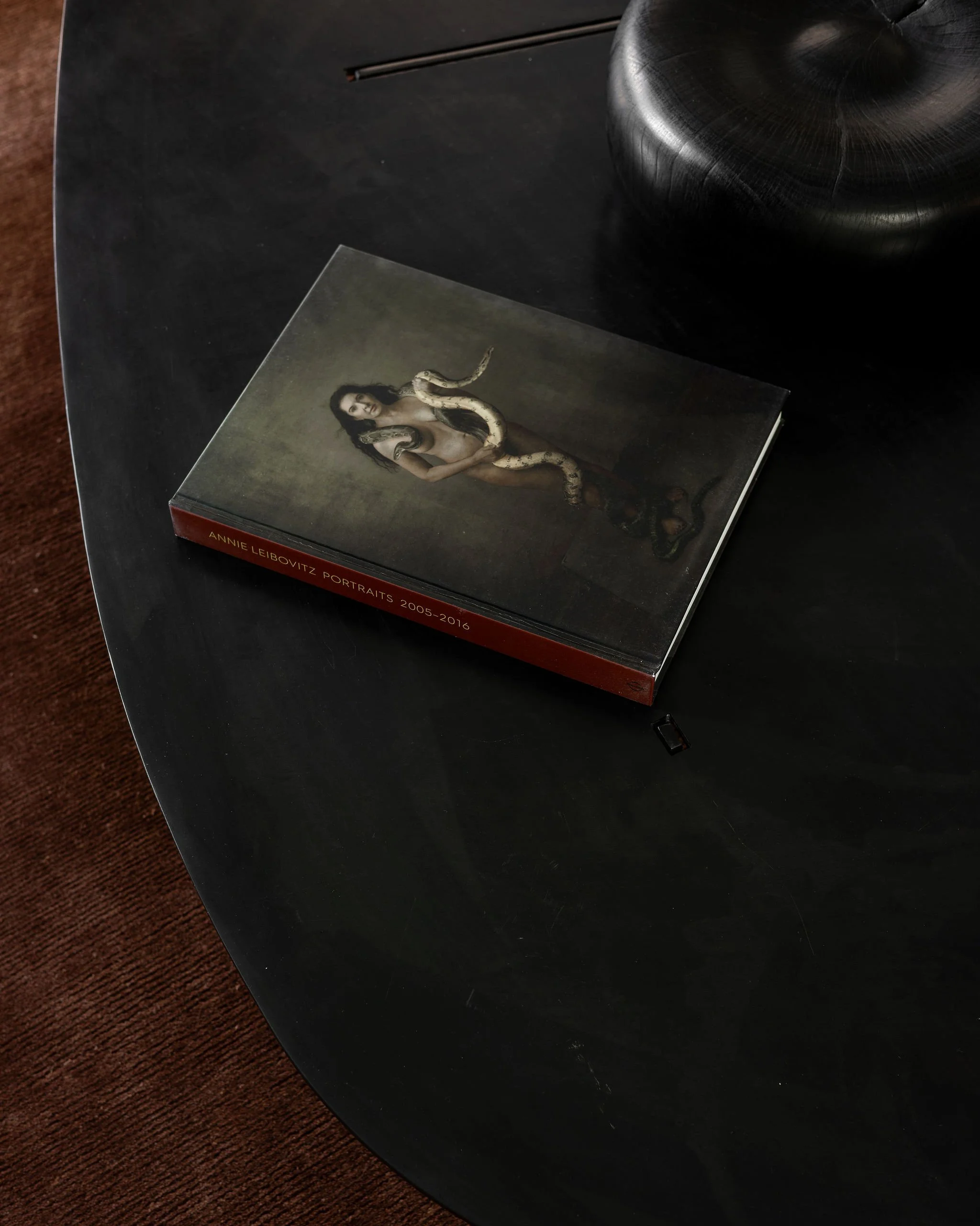 Detail of the sculptural steel coffee table by J.M. Szymanski styled with an Annie Leibovitz photography book and a minimalist wood sculpture.