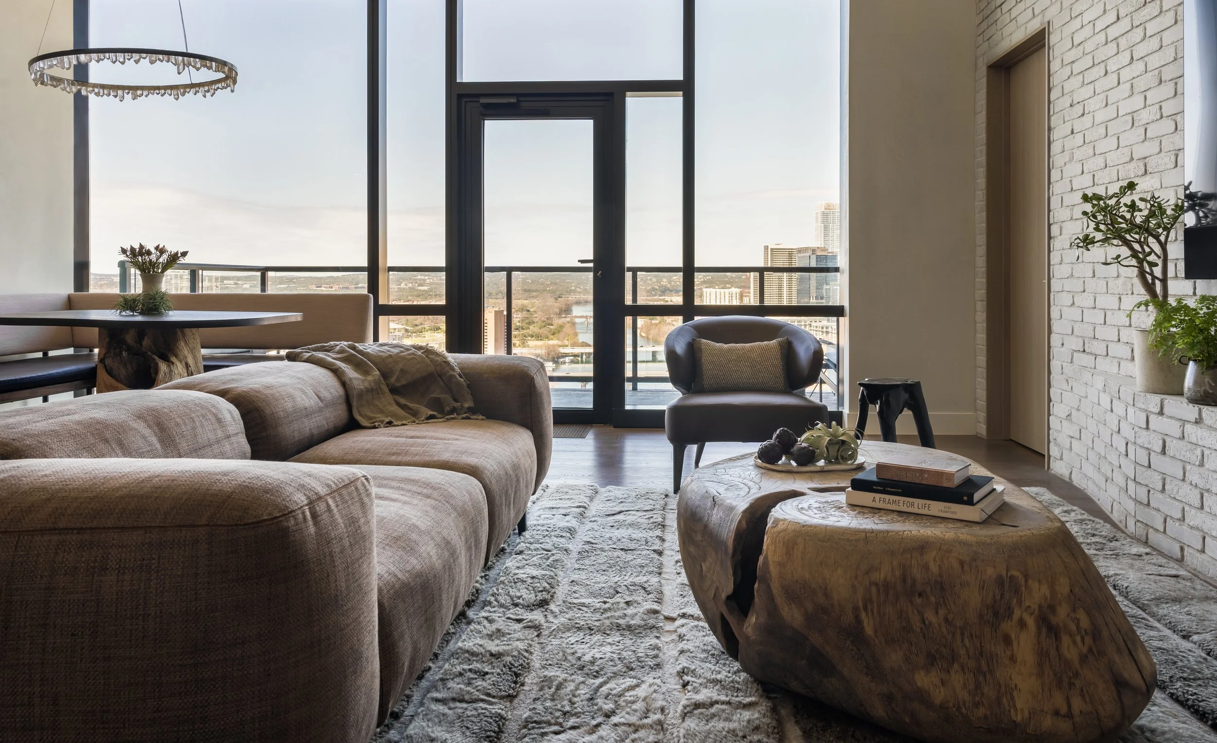 Living room of a Rainey Street condo in downtown Austin featuring a Cassina sofa, sculptural solid wood coffee table, Minotti leather lounge chair, and expansive city views.