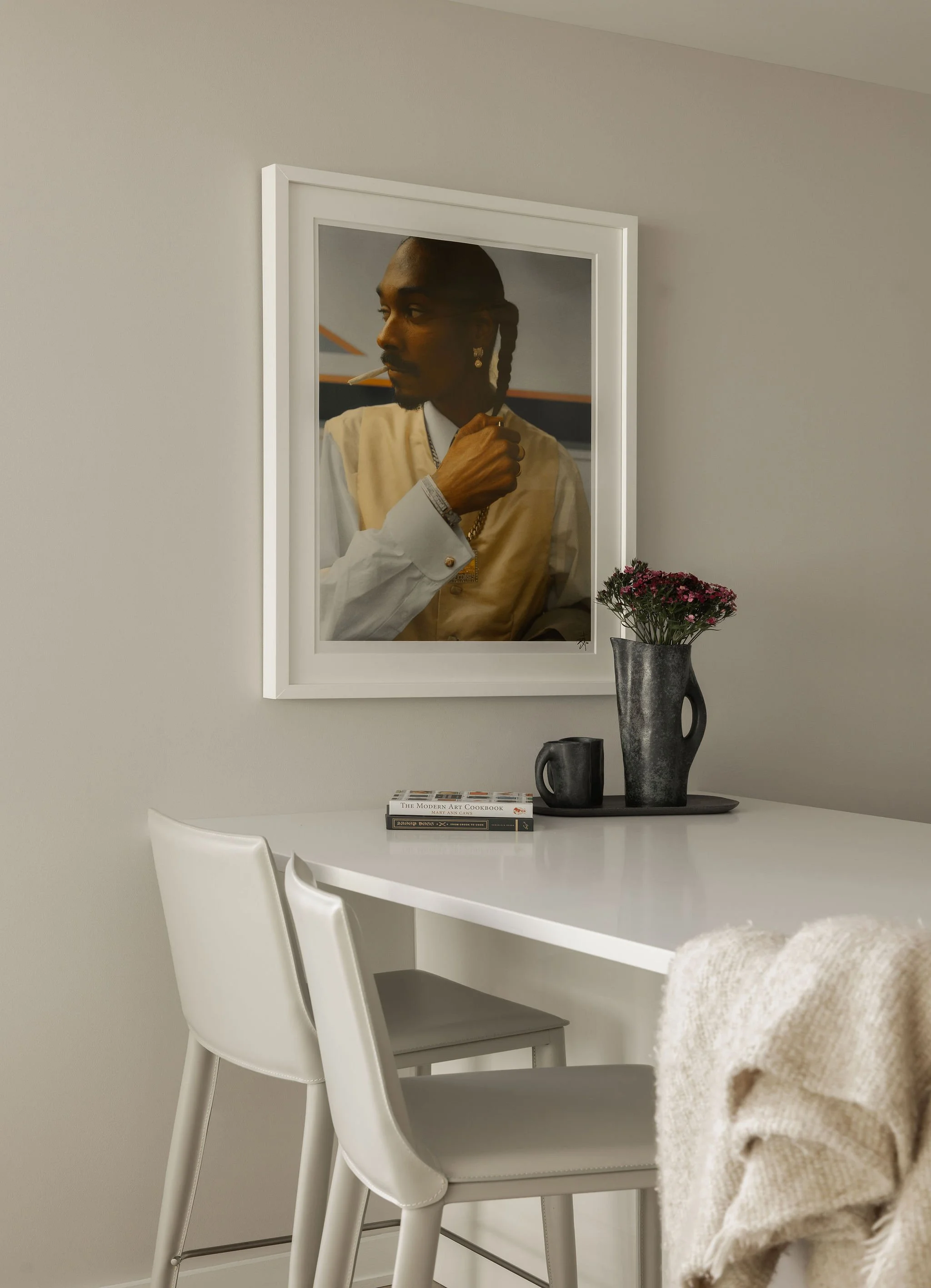 Georgetown condo kitchen by Laura Roberts Design with white countertops, leather barstools, and a framed portrait photograph of Snoop Dogg.