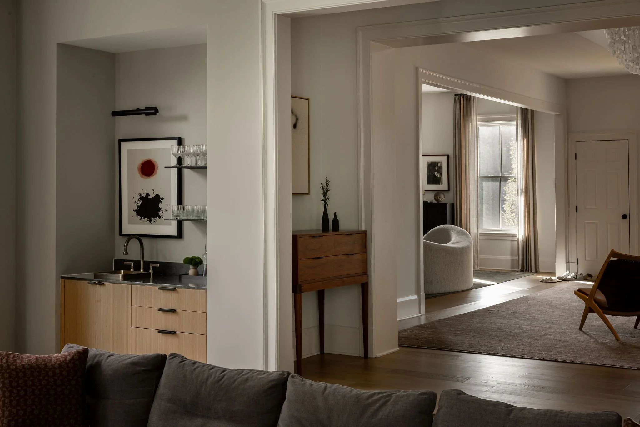 View from the family room into the living room of a McLean, VA home, highlighting layered sightlines and a custom Thos. Moser cabinet that bridges traditional and modern design.