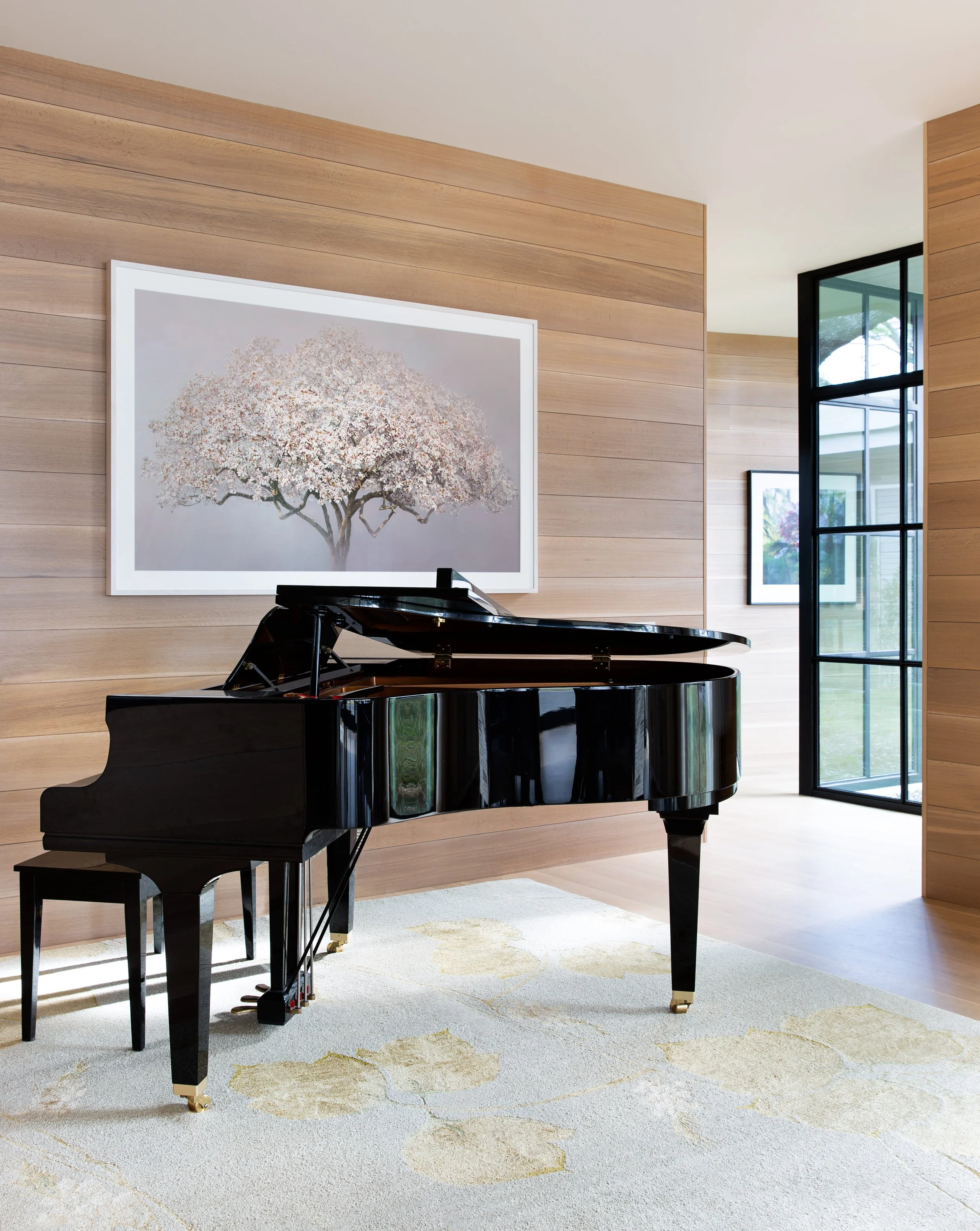 Music room with baby grand piano, white oak shiplap walls and floors, and large magnolia photograph by Irene Kung.