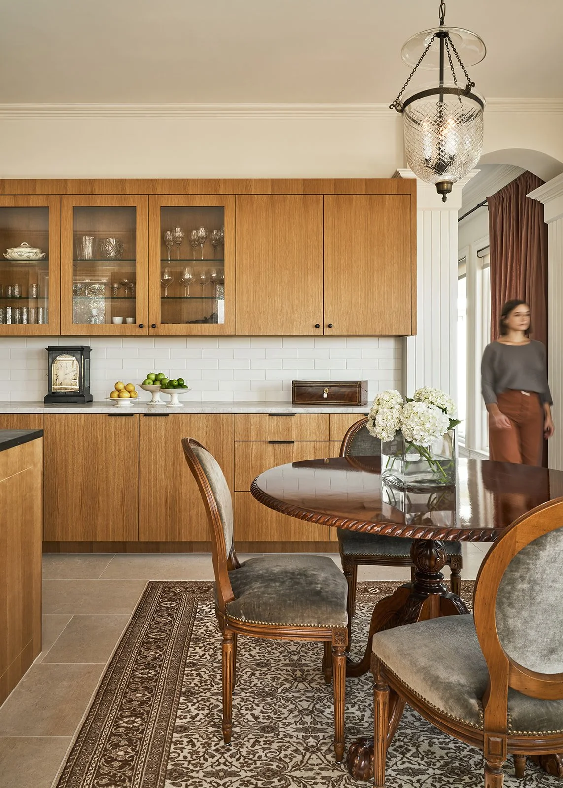 Remodeled Austin kitchen featuring custom inset white oak cabinetry, Taj Mahal quartzite countertops, Ann Sacks tile backsplash, Leuders limestone floors, and a vintage round dining table with chairs styled by Laura Roberts Design.