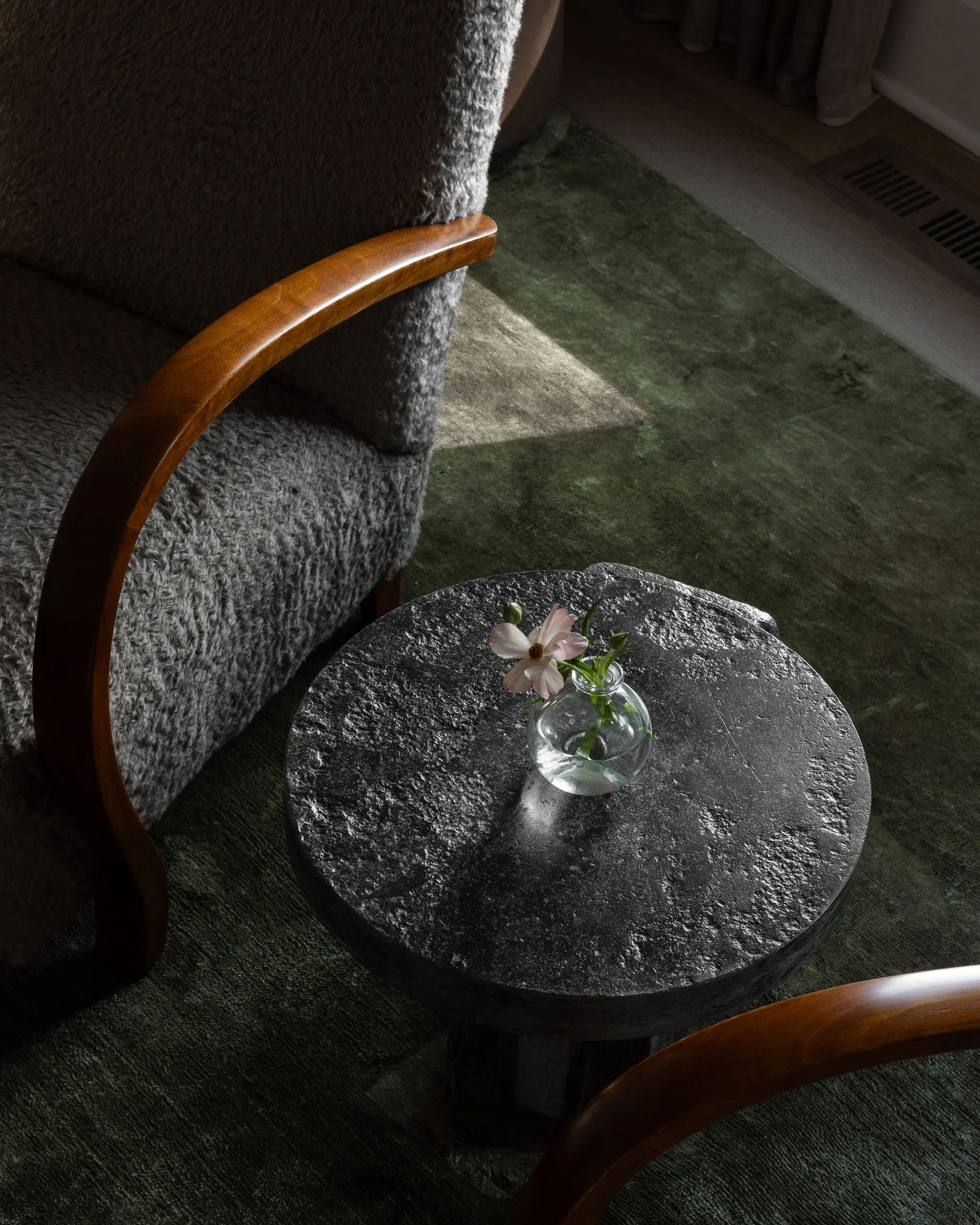 Detail of reupholstered vintage cabinetmaker chairs with a stone side table by Maverick Lee and a deep forest green linen rug in a McLean, VA living room.