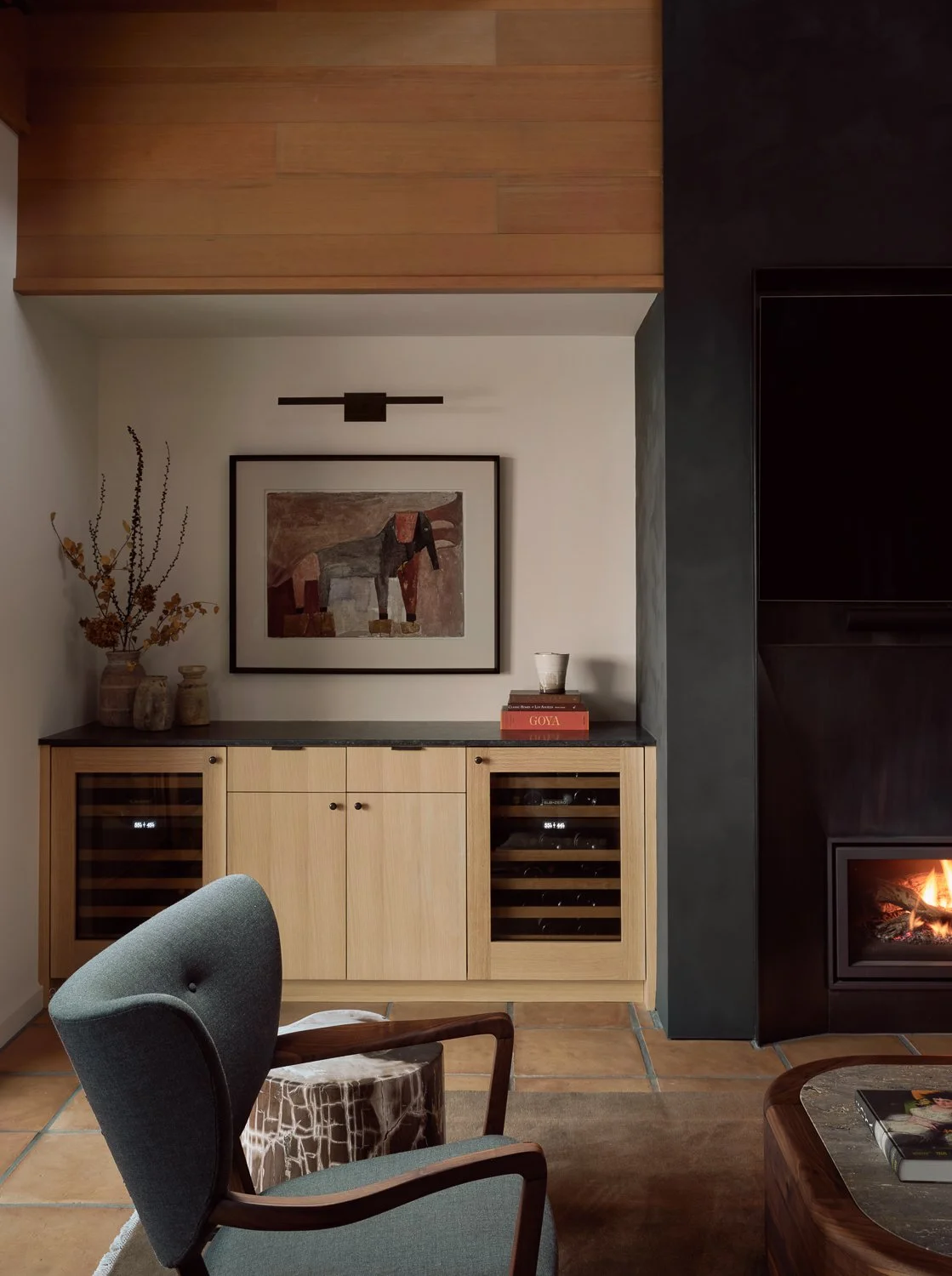 Family room featuring a remodeled bar with custom white oak cabinetry, integrated wine storage, and a black plaster fireplace surround in a Sonoma wine country home.