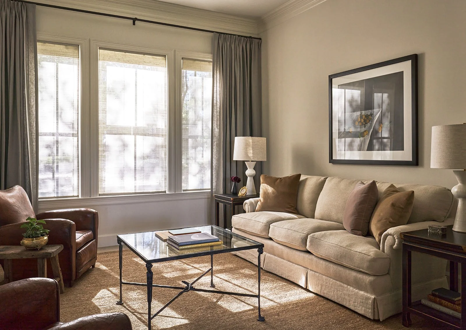Front sitting room in an Austin interior design project featuring a reupholstered sofa in Design of the Times linen, Kate Breakey lemon photograph, Paris flea market club chairs, and a bronze coffee table with Caryatids by H. Cordero and Molyneux