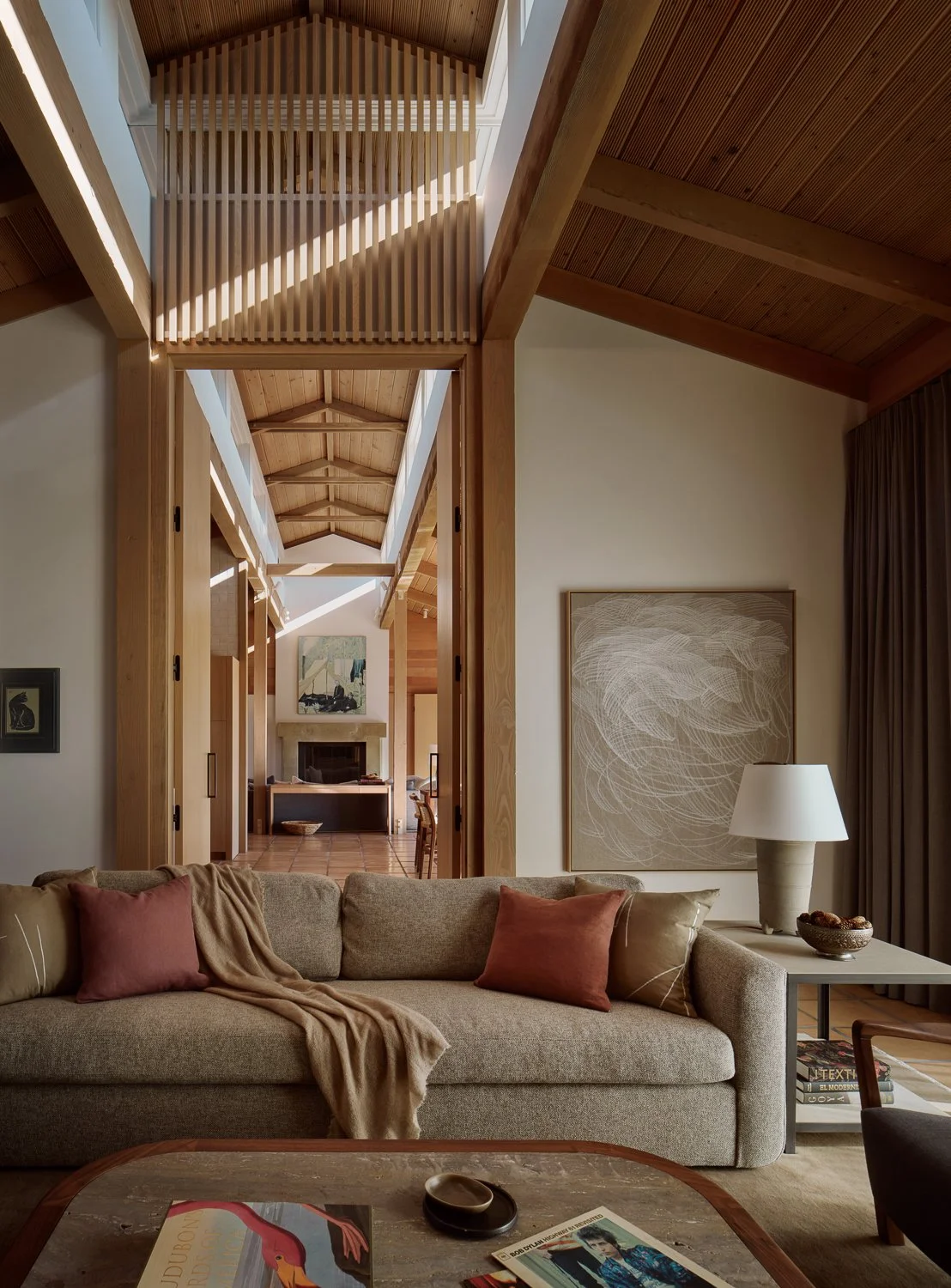 Den in a Sonoma, California home by Laura Roberts Design, featuring a Verellen sofa, custom coffee table and side table by Petrified Design and a large abstract painting by Athamy Armas, with a view through white oak doors to the living room beyond.