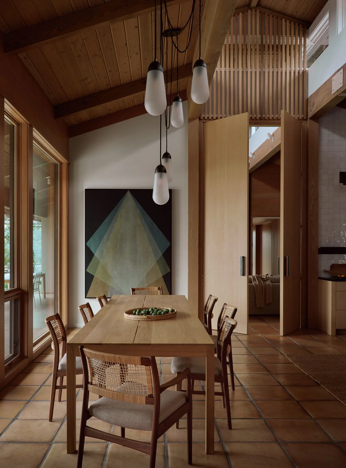 Dining room anchored by a commissioned Gonzalo Lebrijo painting above a custom white oak dining table, illuminated by clerestory light and framed by dramatic white oak doors.
