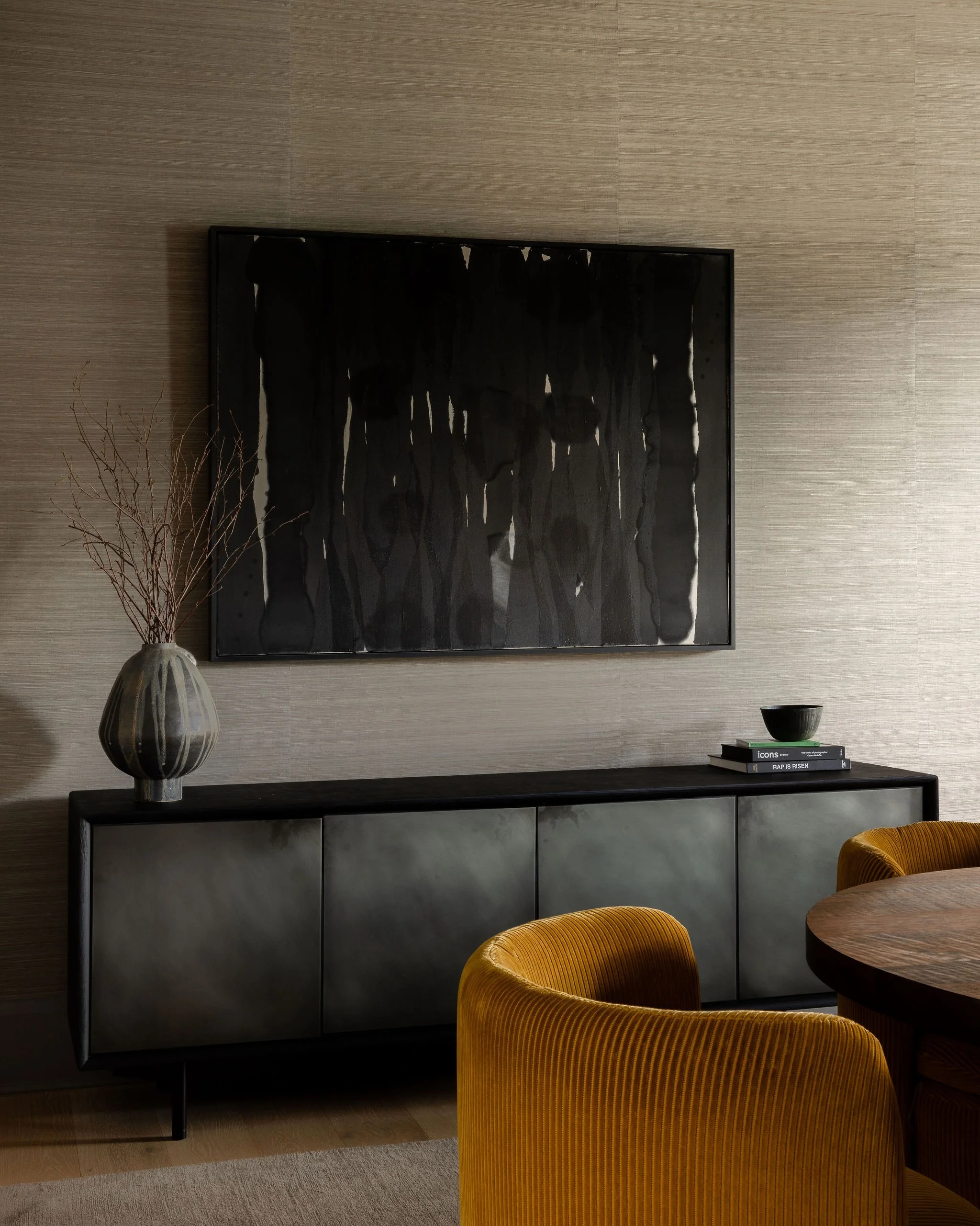 Dining room view in a McLean, VA home with a large abstract painting by Ian McKeever, a modern Wüd credenza, a sculptural moon vase by Jane Yang D’Haene, and mustard upholstered dining chairs.