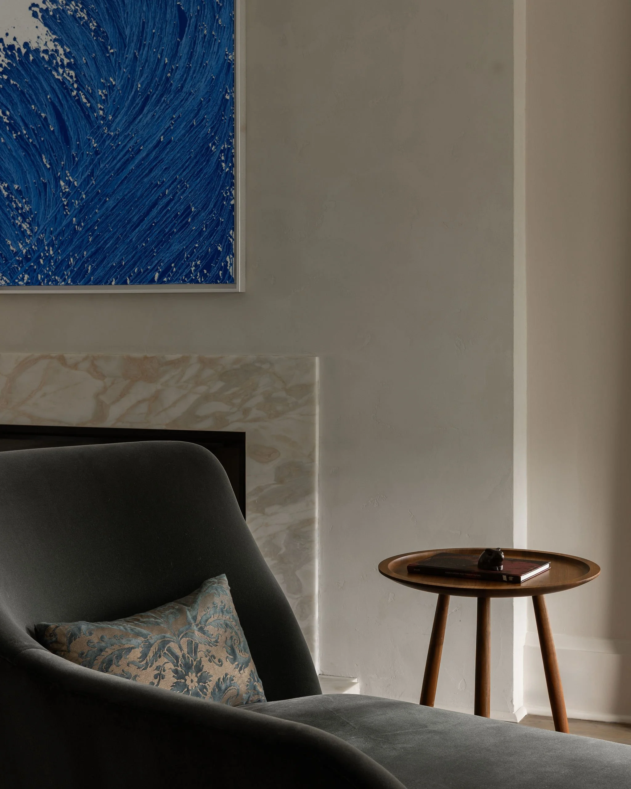 Primary bedroom detail in a McLean, VA home featuring a plaster and marble fireplace, painting by Chae Sung-Pil, and a custom Pinch chaise with a Fortuny silk pillow.