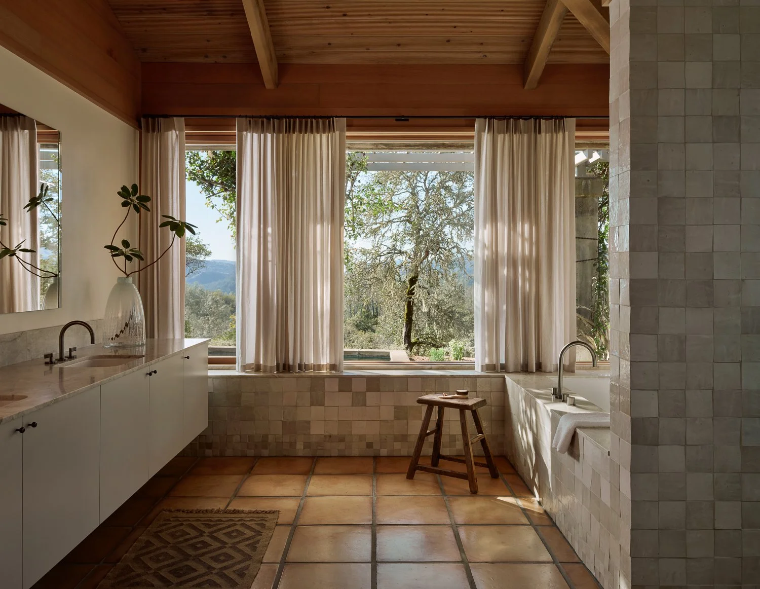 Primary bathroom in a Sonoma wine country home featuring original Saltillo tile floors, a wall-hung vanity in Taj Mahal quartzite, handcrafted zellige tile, and tranquil views to the surrounding landscape.
