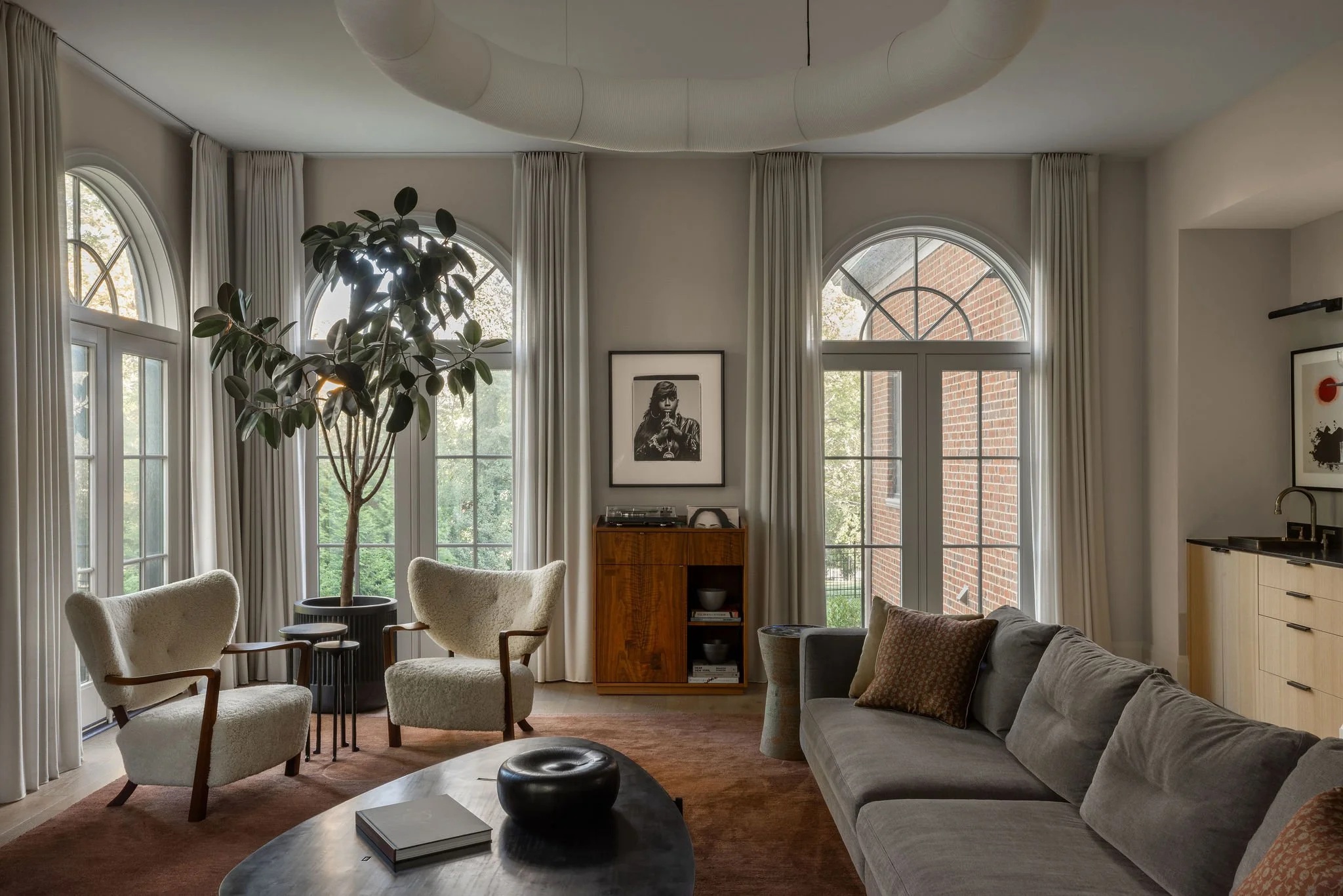 Family room in a McLean, VA home with a custom record cabinet beneath a Missy Elliott photograph, Minotti sectional, Wulff lounge chairs, sculptural coffee table by J.M. Szymanski, and a paper chandelier by Santa & Cole.