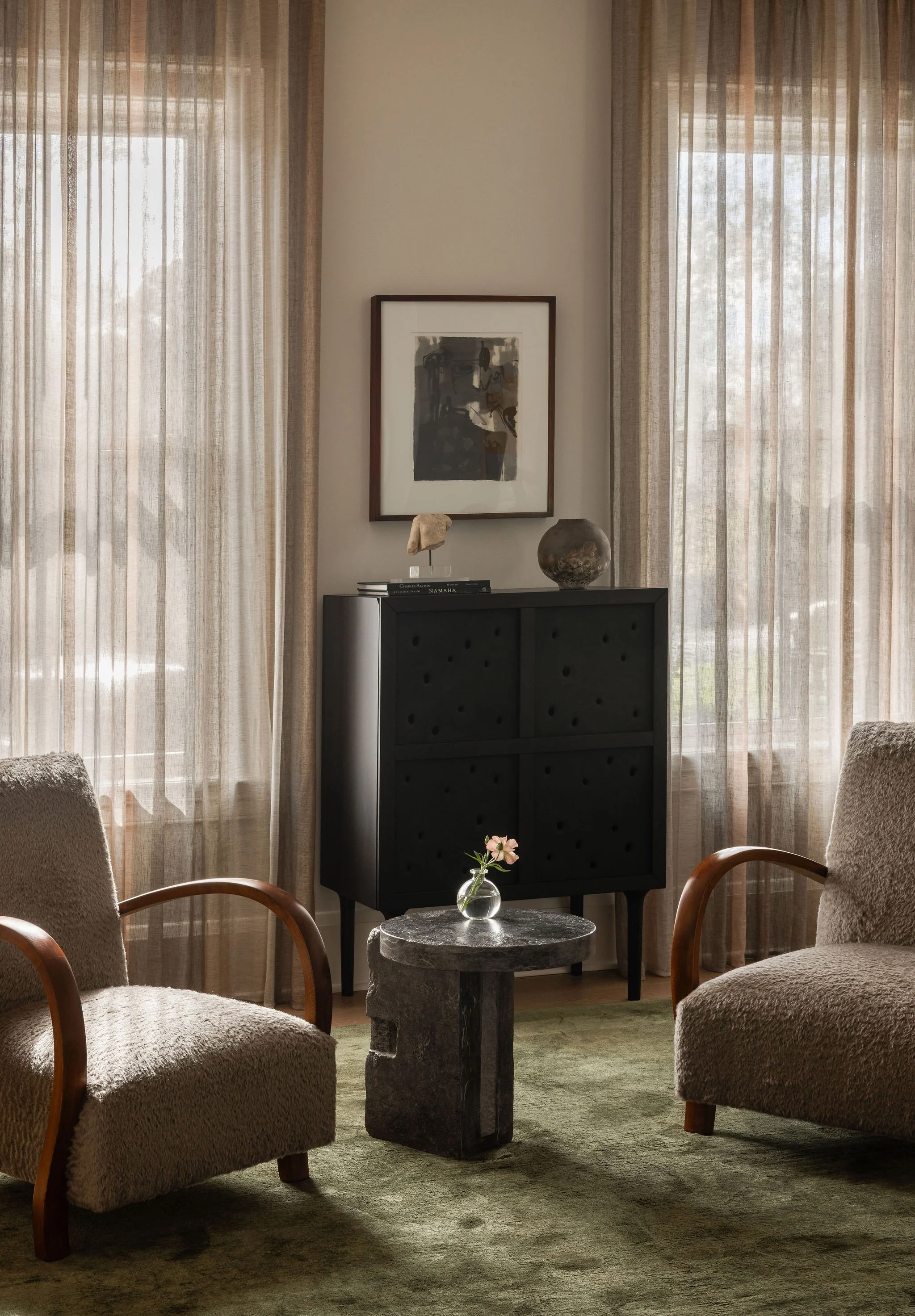 Front living room bar vignette in a McLean, VA home featuring a sculptural concrete-paneled cabinet from Ukraine, artwork by Charles Alston, vintage cabinetmaker chairs, sheer drapery by de Le Cuona, and a carved stone side table by Maverick Lee.
