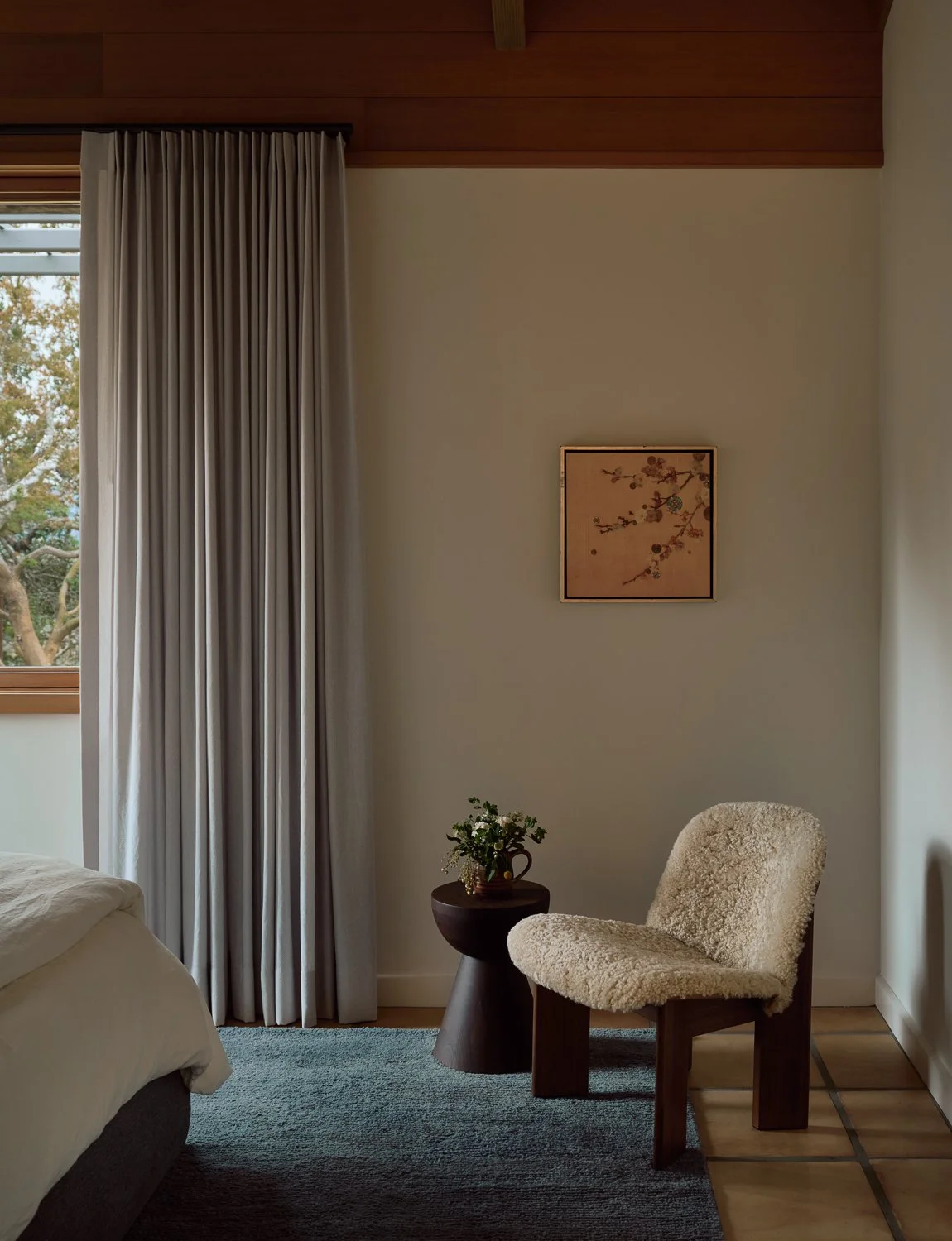 Guest bedroom by Laura Roberts Design with a sculptural lounge chair, custom window treatments, and a serene, nature-inspired palette.
