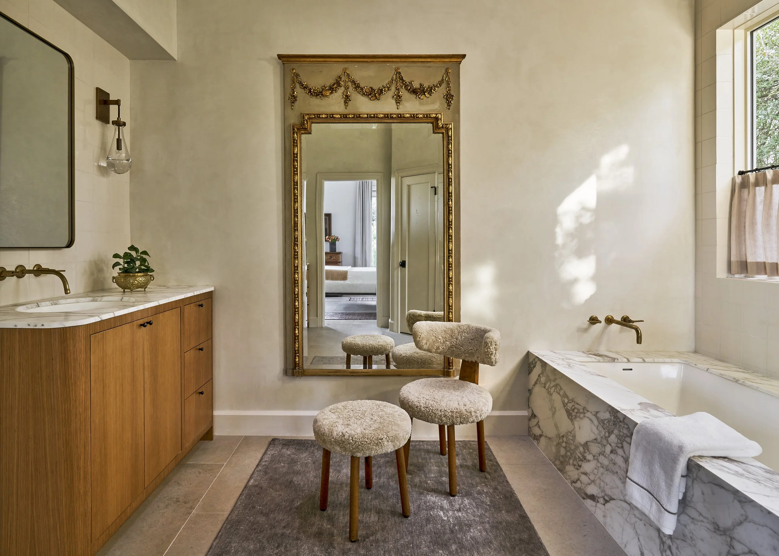 Luxury Austin bathroom interior with marble tub enclosure, custom wood vanity, plaster walls, Van Ghent linen rug and antique trumeau mirror designed by Laura Roberts Design