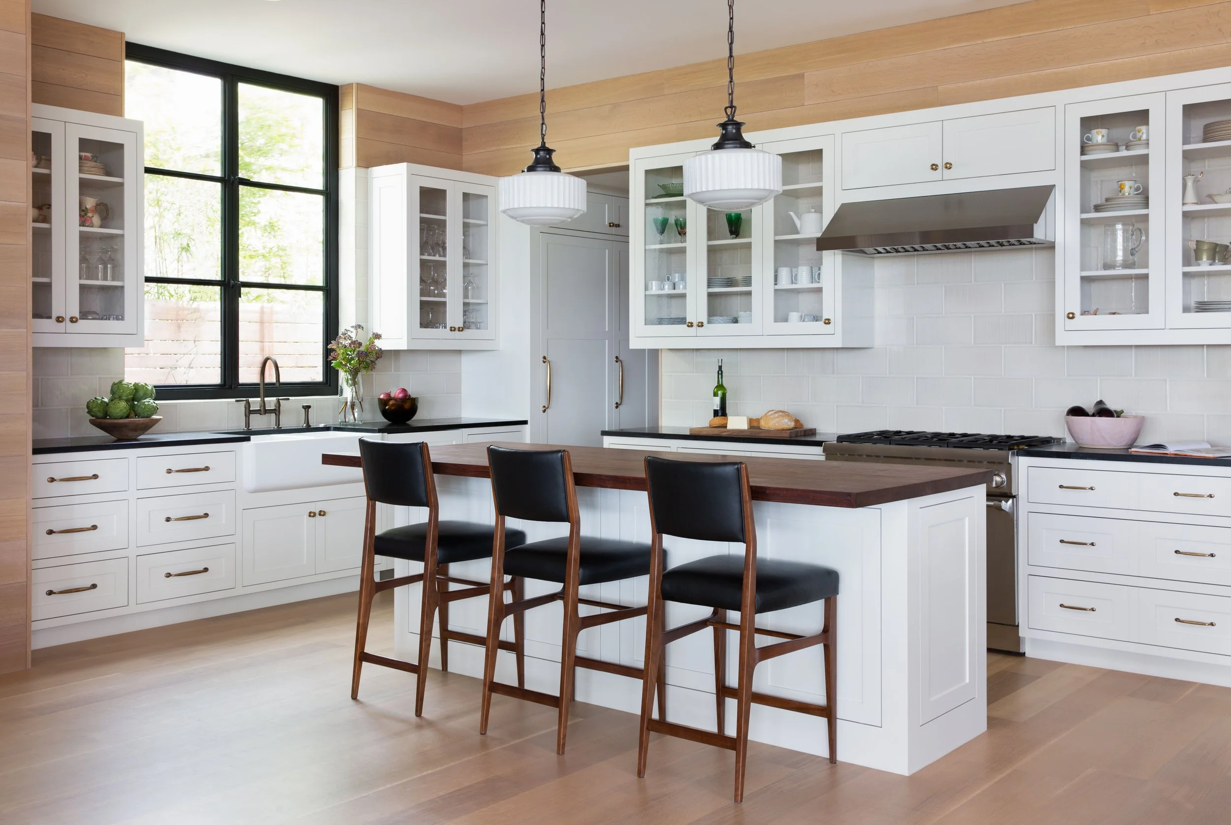 Austin kitchen with custom inset painted cabinetry, walnut island, soapstone countertops, schoolhouse pendants, steel window, and integrated appliances.